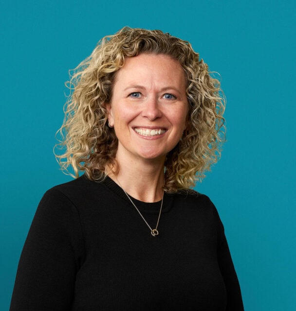 Professional headshot of Kimberly Parker-Maloney, APRN-CNP, smiling in black sweater against blue background