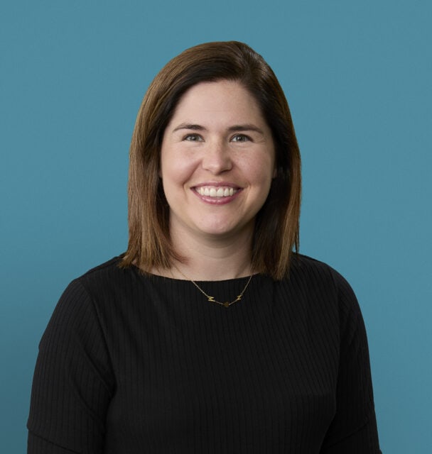 Professional headshot of Kristen Morrison, PA-C, smiling in black sweater against blue background