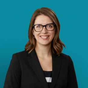 Professional headshot of Dr. Kristen Young smiling in black blazer against teal background
