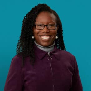 Professional headshot of Dr. Kuwong Mwamukonda smiling in purple jacket against teal background
