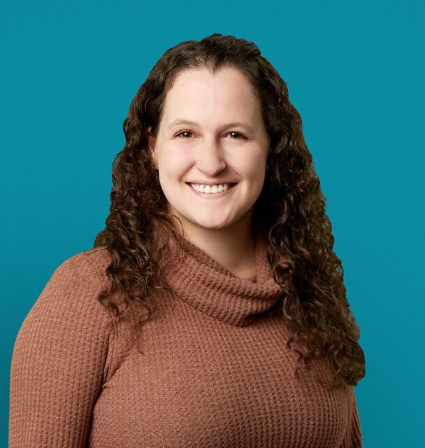 Professional headshot of Leah M. Liddy, APRN-CNP in brown sweater against teal background