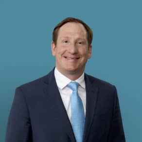 Professional headshot of Dr. Lex P. Leonhardt in navy suit with blue tie