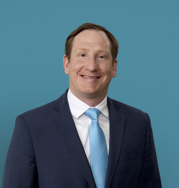 Professional headshot of Dr. Lex P. Leonhardt in navy suit with blue tie