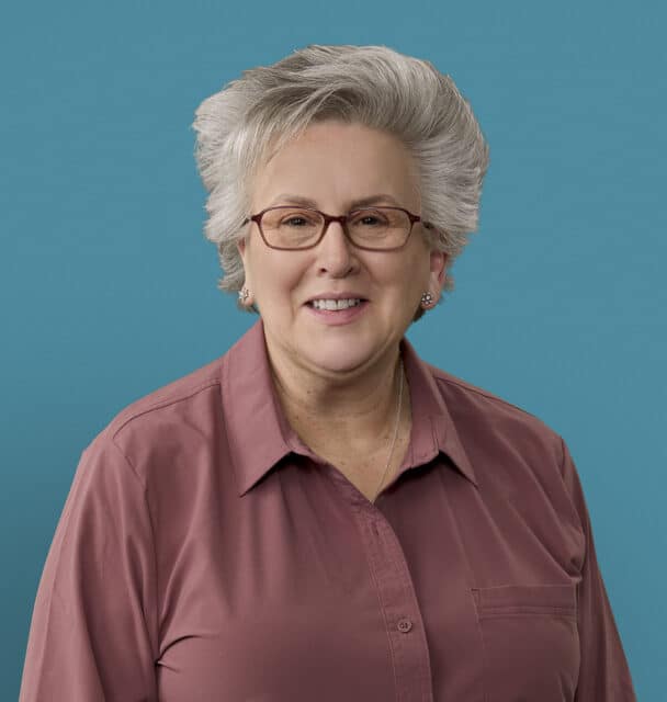 Professional headshot of Linda Vaders, APRN-CNP, smiling in maroon shirt with glasses