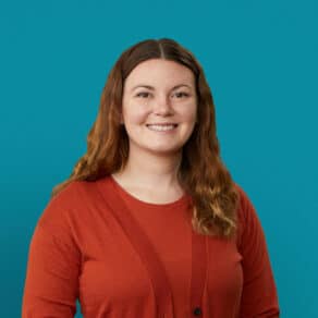 Professional headshot of Madelynn Owens, PA-C in red cardigan against teal background