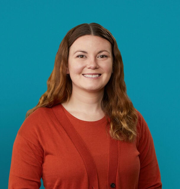 Professional headshot of Madelynn Owens, PA-C in red cardigan against teal background