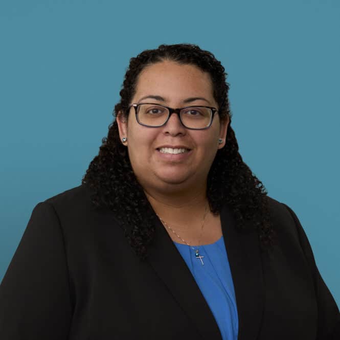 Professional headshot of Dr. Mara Bryan wearing glasses and dark blazer with blue shirt.