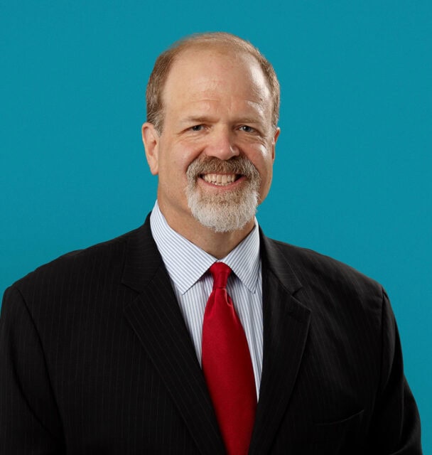 Professional headshot of Dr. Mark W. Moronell in dark suit with red tie