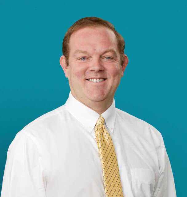 Professional headshot of Matthew Garrett, MD, PhD in white shirt and yellow tie