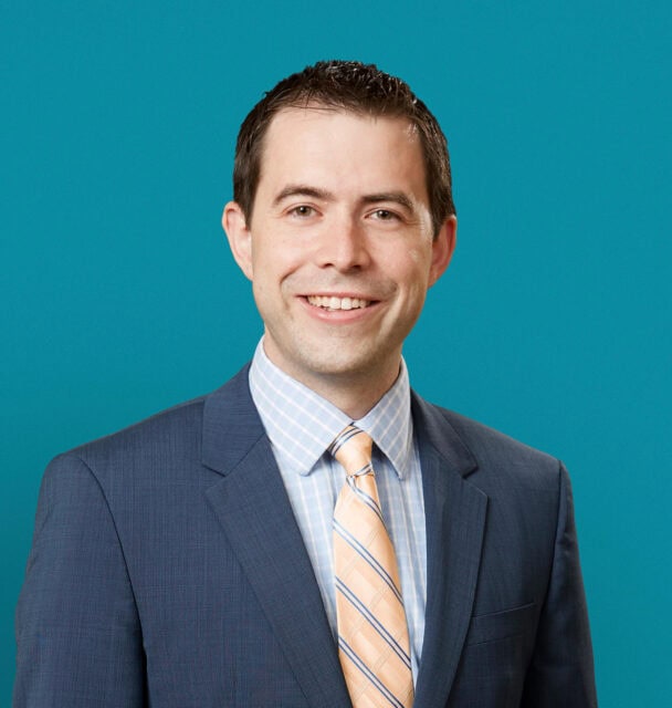 Professional headshot of Dr. Matthew L. Knecht in business suit against teal background