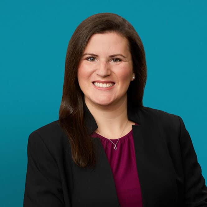 Professional headshot of McKayla Riggs, MD wearing black blazer and purple blouse
