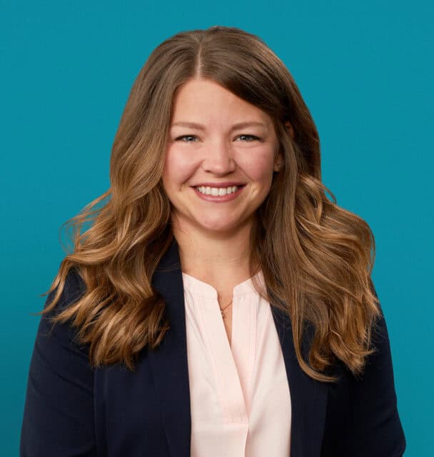 Professional headshot of Megan Kuertz, APRN-CNP, smiling in business attire against teal background.