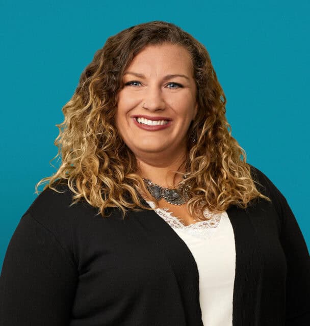 Professional headshot of Melissa Einink, APRN-CNP, smiling woman with curly blonde hair in black cardigan.