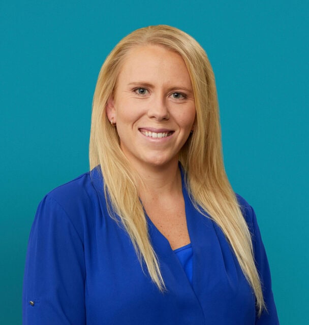 Professional headshot of Melissa Geyer, APRN-CNP in blue medical scrubs smiling at camera