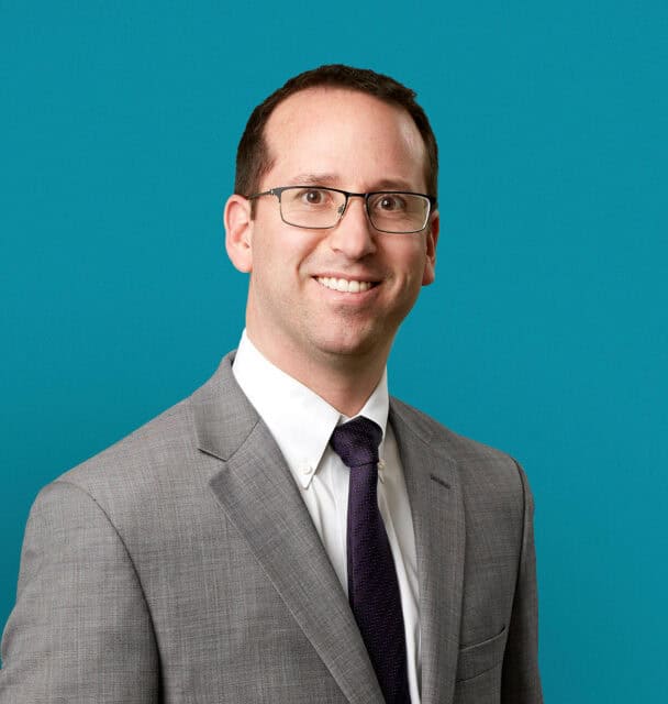 Professional headshot of Michael D. Johnson, MD in gray suit against teal background