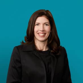 Professional headshot of Dr. Mollie E. Strauchon in dark blazer against teal background