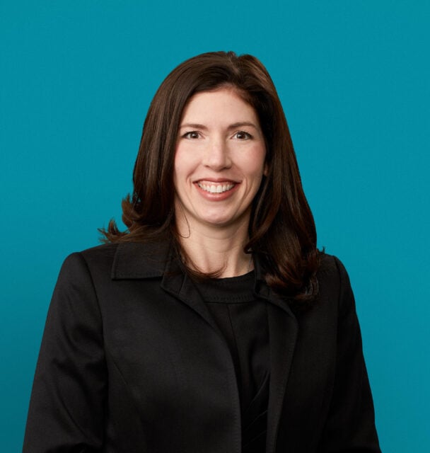 Professional headshot of Dr. Mollie E. Strauchon in dark blazer against teal background