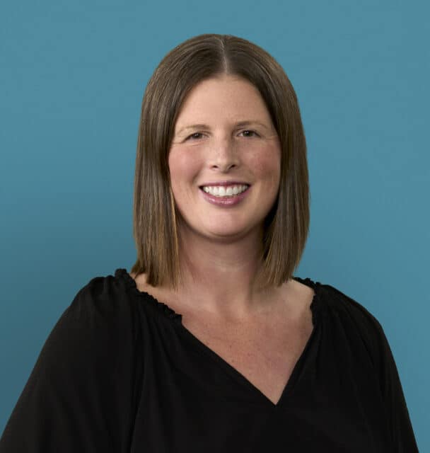 Professional headshot of Molly Bowman, RN, smiling in black top against blue background