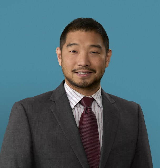 Professional headshot of Moses Chung, PA-C in gray suit with burgundy tie