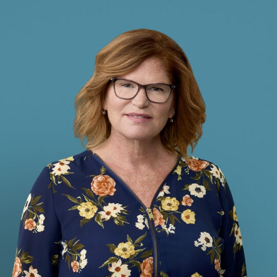 Professional headshot of Nancy Hall, APRN-CNP wearing floral blouse and glasses