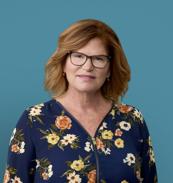 Professional headshot of Nancy Hall, APRN-CNP wearing floral blouse and glasses