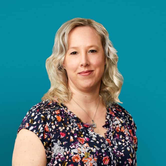 Professional headshot of Nicole "Nikki" Buckingham, APRN-CNP in floral top against teal background