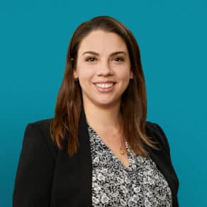Professional headshot of Nicole Thomas, PharmD smiling in black blazer against teal background