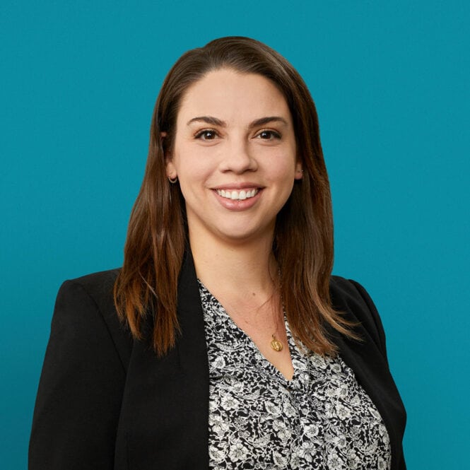 Professional headshot of Nicole Thomas, PharmD smiling in black blazer against teal background