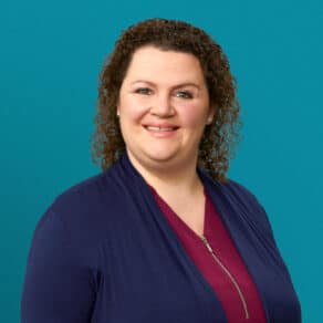 Professional headshot of Olivia Aikman, APRN-CNP, smiling in navy cardigan and red top