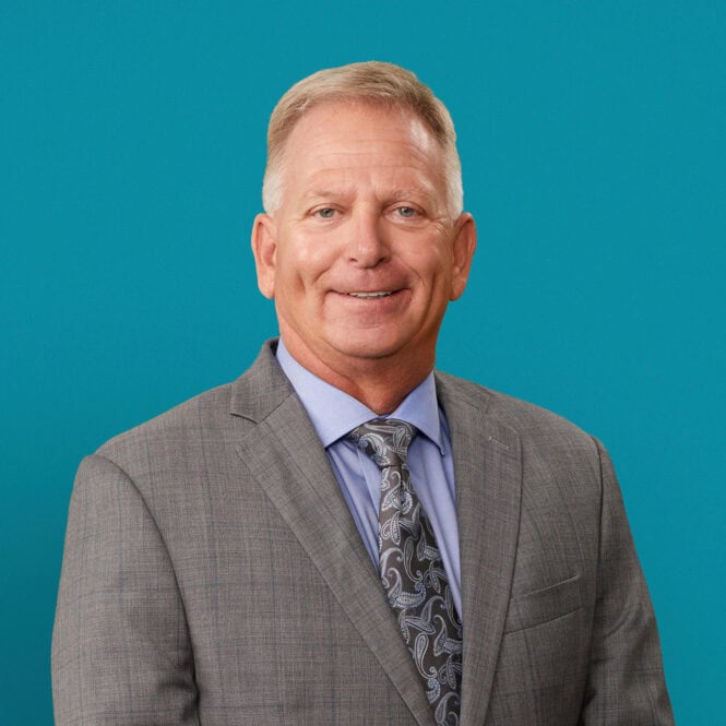 Professional headshot of Patrick J. Lytle, DO in gray suit against teal background