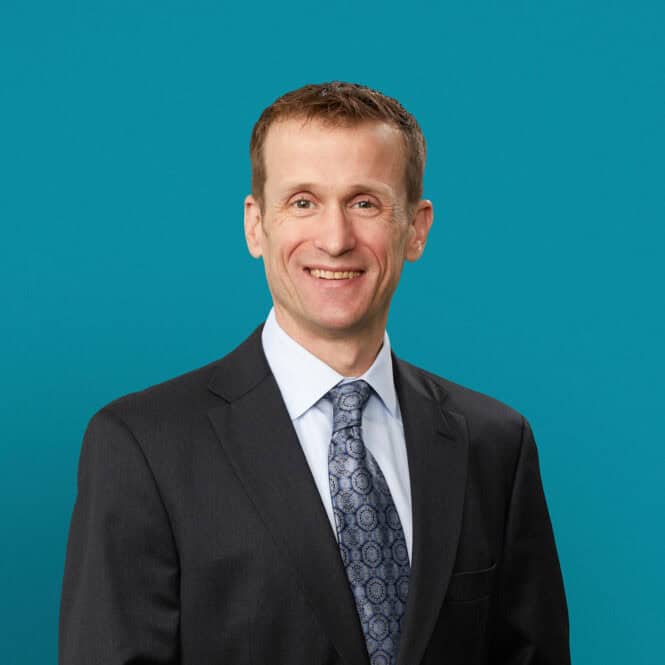 Professional headshot of Dr. Paul G. Peters in dark suit against teal background