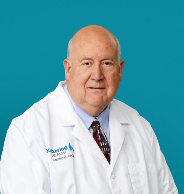 Professional headshot of Dr. Philip S. Perona in white medical coat against teal background