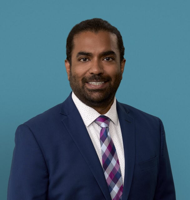 Professional headshot of Dr. Phillip Yohannan in navy suit against blue background