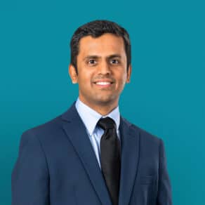 Professional headshot of Dr. Pratik M. Choksy in navy suit against teal background