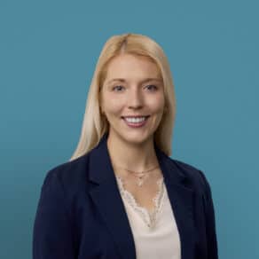 Professional headshot of Rachael Bauer, PA-C in navy blazer against teal background