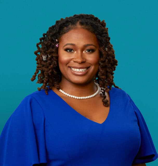 Professional headshot of Rachelle Dulan Hood, DO wearing blue top with pearl necklace