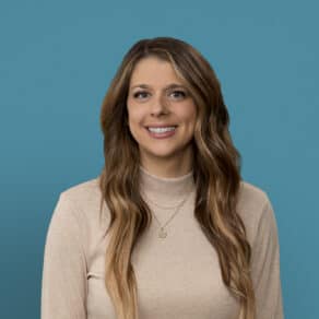 Professional headshot of Rebecca Klark, APRN-CNP, smiling in beige top against blue background