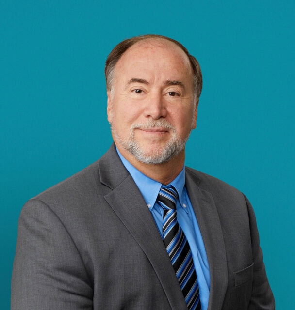 Professional headshot of Richard K. Smith, DO in gray suit with blue striped tie