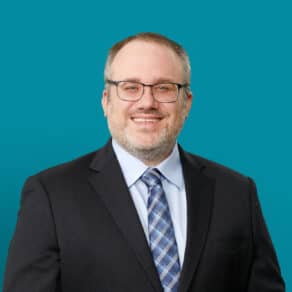 Professional headshot of Robert Polak, MD smiling in dark suit against teal background