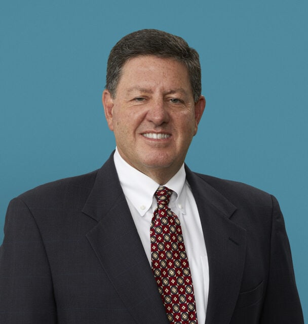 Professional headshot of Robert T. McClure, MD in dark suit with red patterned tie