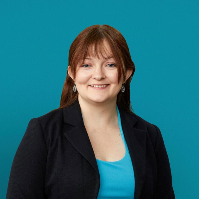 Professional headshot of Sarah Dula, DO in black blazer against teal background