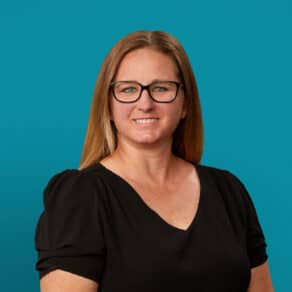 Professional headshot of Shannon Lewis, APRN-CNP, smiling in black top against teal background.