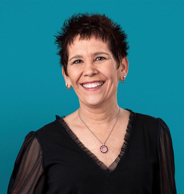 Professional headshot of Dr. Shelli A. Powell smiling in black top against teal background