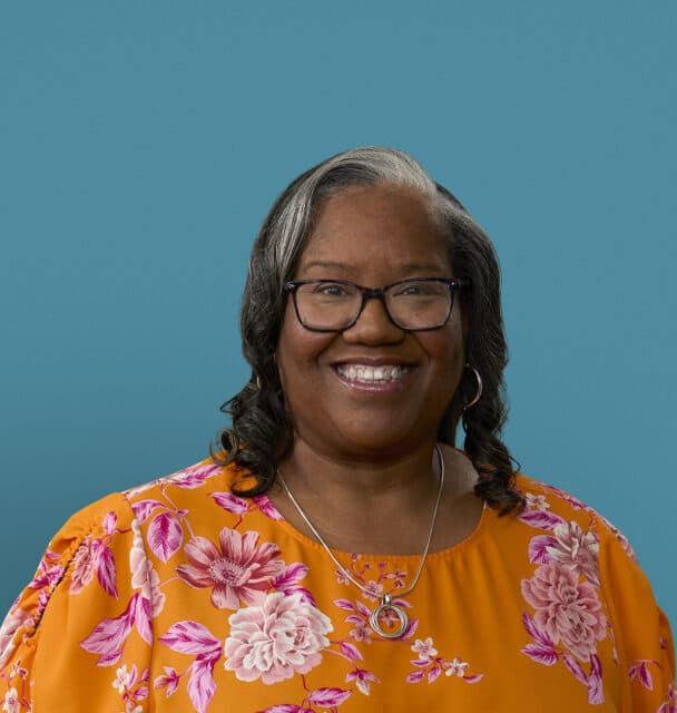 Professional headshot of Dr. Shirelle Applin wearing orange floral top and glasses