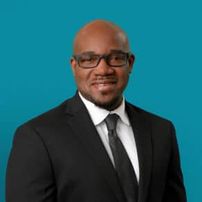 Professional headshot of Stedman E. Hughes, APRN-CNP in business attire against teal background