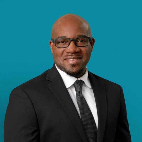 Professional headshot of Stedman E. Hughes, APRN-CNP in business attire against teal background