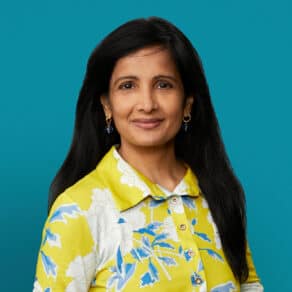 Professional headshot of Dr. Sunita M. Reddy wearing yellow floral shirt against teal background