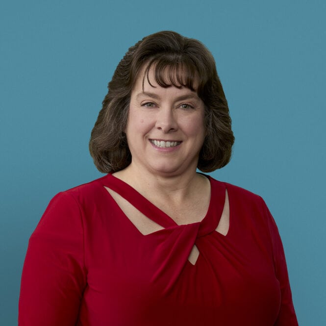 Professional headshot of Teresa VanHoose, APRN-CNP in red top against blue background