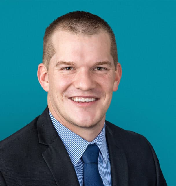 Professional headshot of Thomas A. Koroscil, MD in dark suit with blue tie