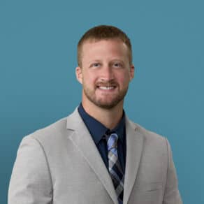 Professional headshot of Zachariah P. Zehler, APRN-CNP in light gray suit and tie